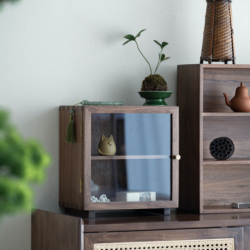 Closed Agni walnut cabinet with clear glass door in a room setting