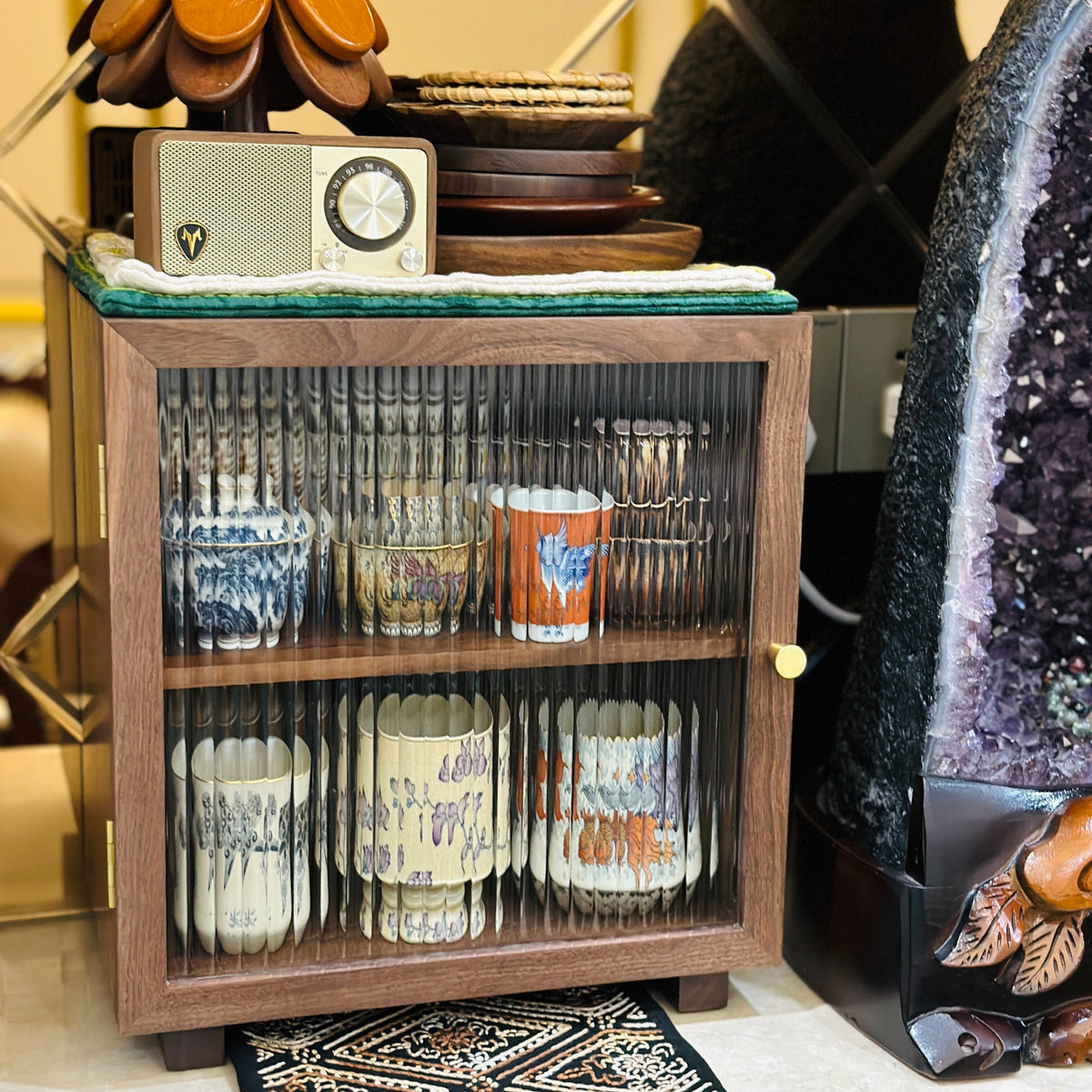Agni walnut cabinet with fluted glass door holding ceramic cups