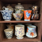 Open Agni walnut storage cabinet filled with ceramic cups