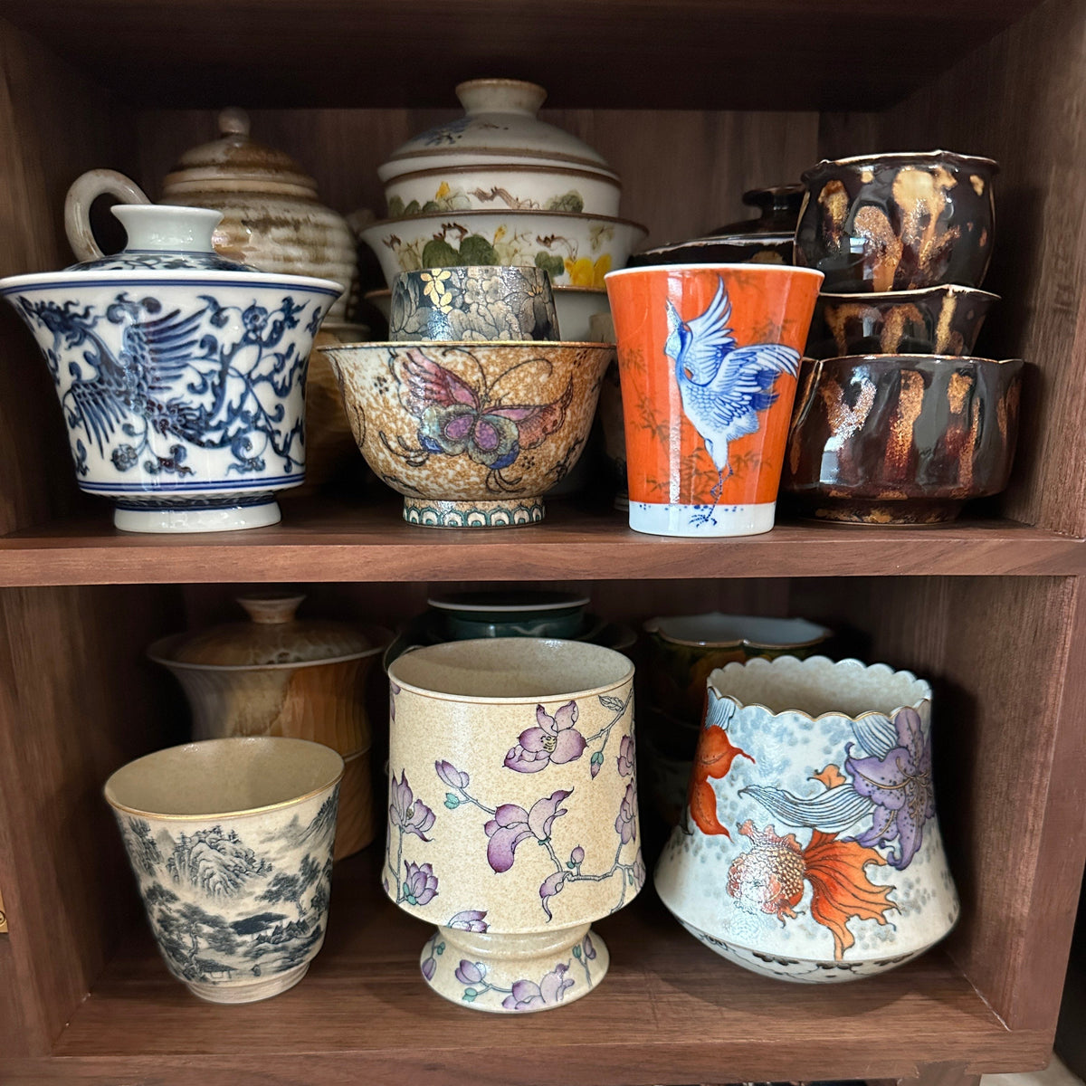Open Agni walnut storage cabinet filled with ceramic cups