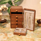 Wooden jewelry organizer with drawers and display case on a floral tablecloth.