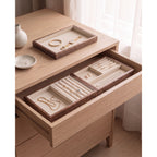 Two walnut jewelry trays side by side in a dresser drawer with a third on the dresser top
