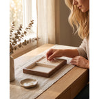 Walnut stackable jewelry tray insert being placed on a dresser top