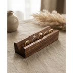 Walnut ring slot wooden display stand with several rings seated in parallel slots