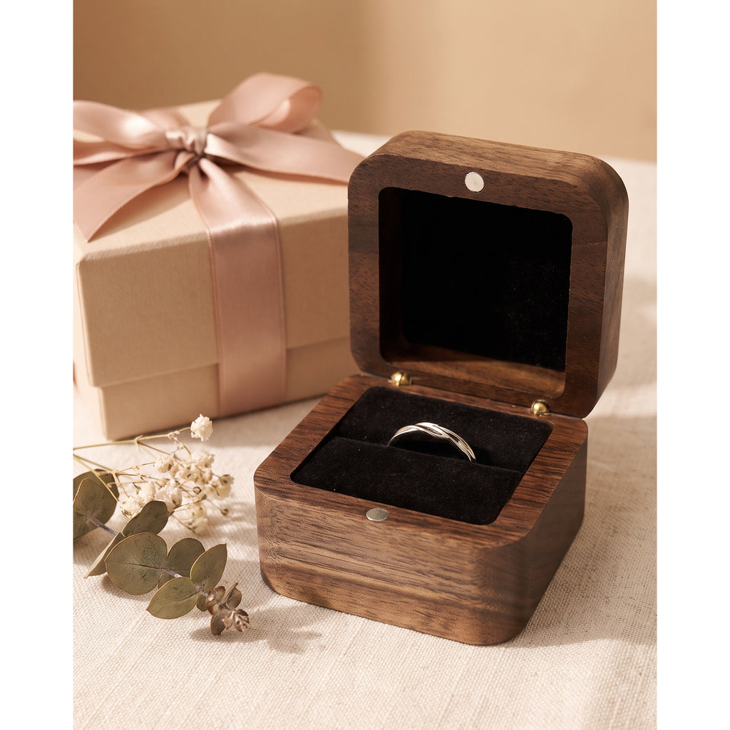 Walnut ring box open beside a ribboned gift box, black velvet ring slot