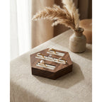 Walnut hexagon ring display stand with three velvet channels, holding several rings